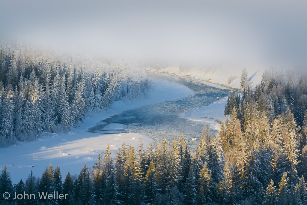 The sun breaks through the fog to light the Snake River in the Tetons.